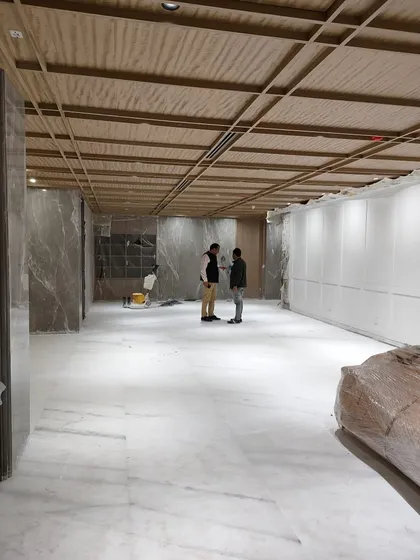 On-site at Hamdard HQ, where marble flooring and a wooden grid ceiling are being installed. This image captures the moment when the material palette begins to define the character of the space.