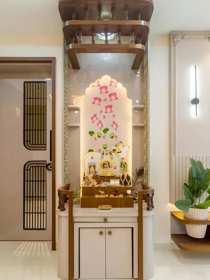 An elegant pooja unit with a beautiful lotus-themed backdrop. The design uses a combination of wood and white finishes, with integrated lighting to create a serene and divine atmosphere.