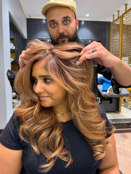 A warm tones hair color balayage that creates a beautiful, sun-kissed effect. The voluminous styling enhances the color's dimension.