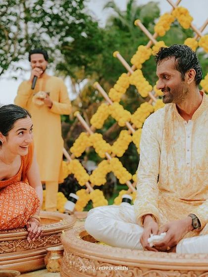 Eli and Suman seated in ornate bowls for their Haldi ritual. The unique setup and the vibrant marigold decorations create a visually stunning scene.