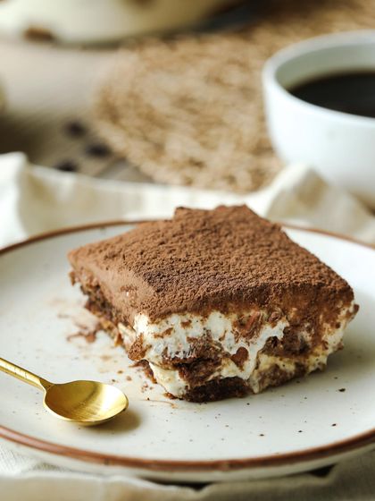 A serving of my Classic Tiramisu on a plate, showing the distinct, coffee-soaked layers. It's a dessert that never fails to please.