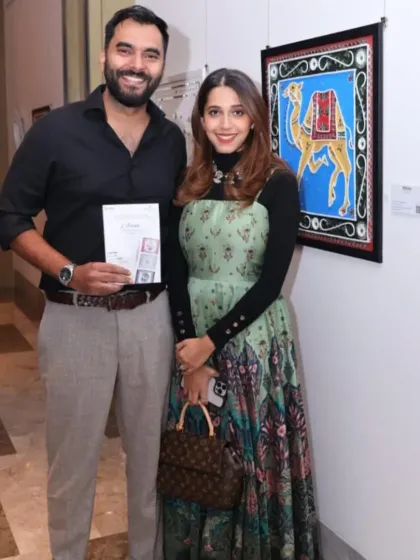 Guests at the 'Aaina' exhibition, posing with a colorful artwork of a camel.