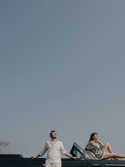 A cool, relaxed pose on a vintage convertible against a clear blue sky. This shot has a cinematic, old-school Hollywood feel, perfect for a stylish Goa pre-wedding album.
