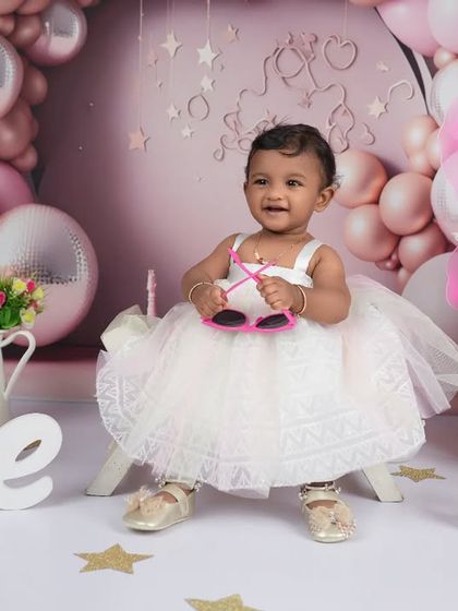 A true star in the making! Adding fun accessories like these heart-shaped sunglasses brings out the playful side of a one-year-old during her milestone photoshoot.