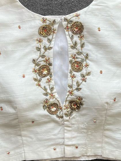 A detailed close-up of the handwork on the white silk blouse.
