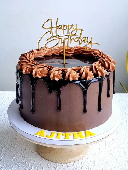 A full view of the chocolate truffle drip cake on its stand.