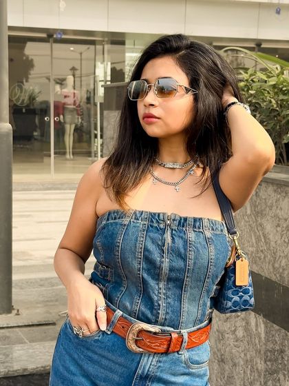 A close-up of the denim on denim look, showing the texture of the tube top and the layered silver necklaces.