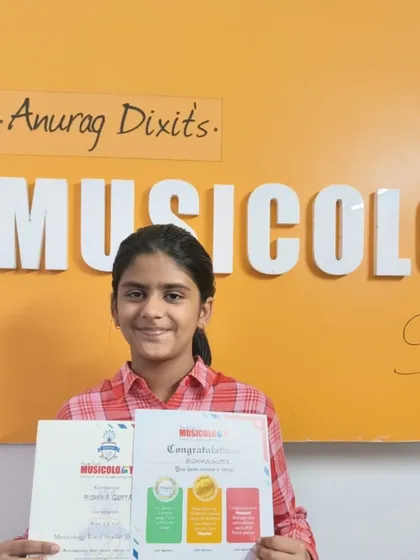 A young student smiles as she holds her Musicology certificate, a great way to build her profile and mark her progress.
