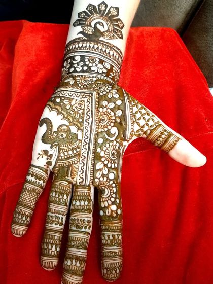 A traditional design for a guest, featuring an elephant motif on the palm. The fingers are decorated with classic bands and patterns.