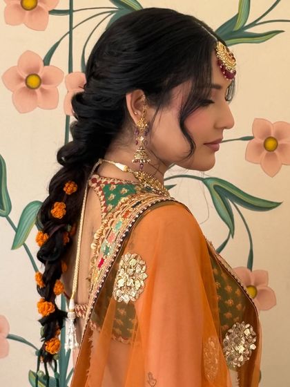 Another side profile of the marigold-adorned braid, set against a floral wallpaper.