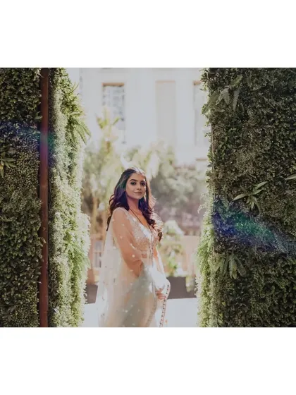 A beautiful portrait of the bride, Shruti, framed by a lush green wall, the natural light creating a lovely flare.