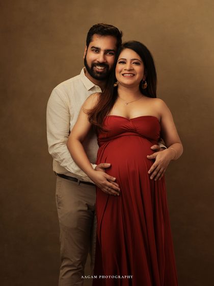 A happy and classic fine art maternity portrait. The couple's bright smiles and the vibrant red dress bring a wonderful energy to this studio session.