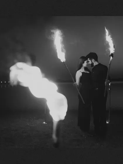 A powerful black and white portrait of a couple surrounded by fire torches, creating a dramatic and intense pre-wedding image.
