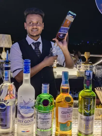 Ready to serve you and your guests with a smile. This was taken at a private party, where I was managing a fully stocked bar featuring premium spirits like Johnnie Walker Blue Label, Grey Goose, and Glenlivet.