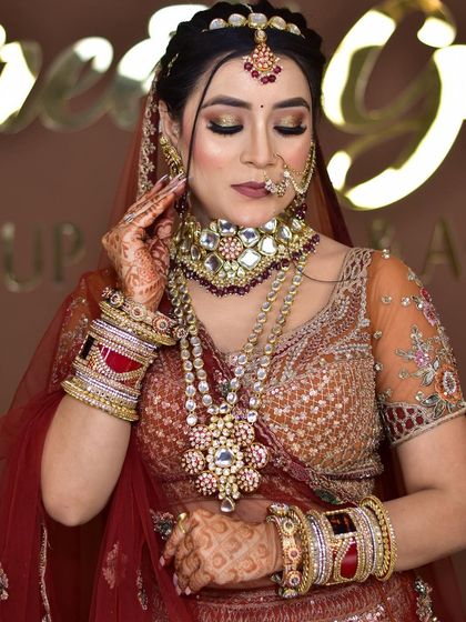 A bride adorned in a heavy, layered Polki and Kundan necklace set. The detailed craftsmanship, complete with a matching matha patti and nath, creates a timeless and royal bridal look.