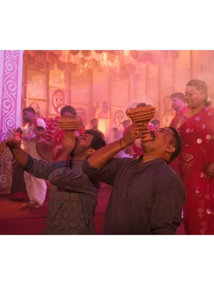 Two men perform the Dhunuchi dance together, showcasing the community aspect of the ritual.