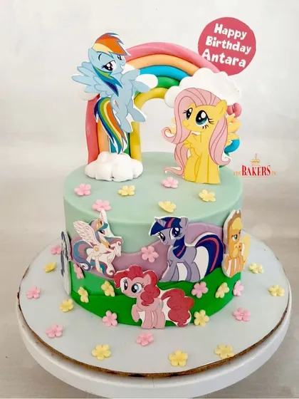 A colorful and cheerful "My Little Pony" cake for Antara's 5th birthday. This minimal-fondant cake features Rainbow Dash, Fluttershy, and the rest of the pony friends on a grassy green field with a big rainbow.
