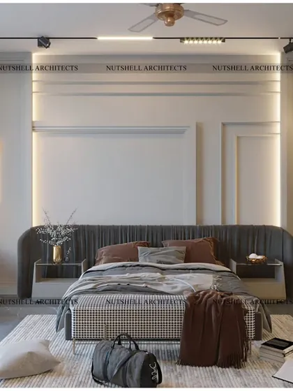 We designed this bedroom to be a tranquil retreat. The space features a clean, minimalist aesthetic with wall moldings, modern light fixtures, and a comfortable bed with an extended upholstered headboard.