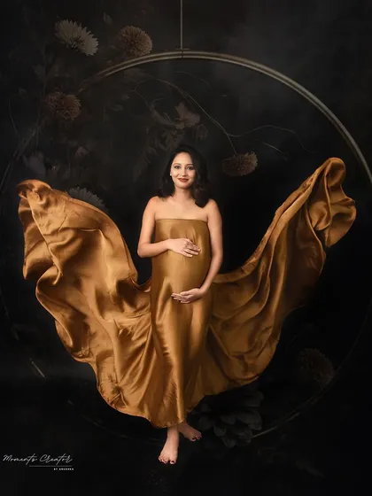 A powerful and centered pose. The golden fabric creates a wing-like effect behind the mom-to-be, framed perfectly by the circular prop in the background.