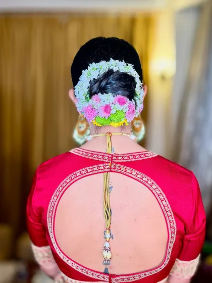 A beautiful view of the floral bridal bun. The combination of white and pink flowers adds a fresh and delicate touch to the traditional hairstyle.