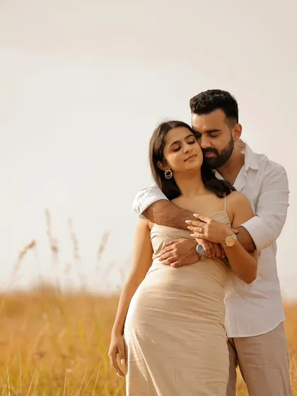 A tender embrace in a field of golden grass. The soft lighting and natural setting create a serene and romantic atmosphere for this pre-wedding portrait.