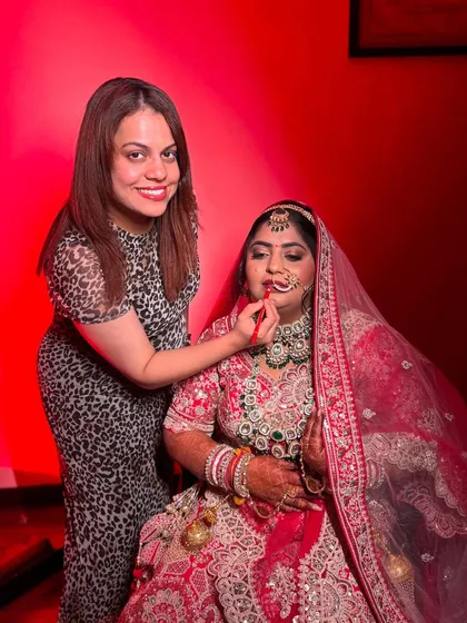 This photo captures the focus and concentration that goes into every makeup application. The vibrant red lighting creates a very glamorous mood.