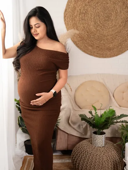 A peaceful moment of reflection by the window. The warm brown dress and the soft, natural light create a calm and serene atmosphere.