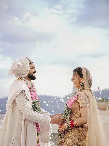 A candid, happy moment during the wedding ceremony, with the couple laughing together as flower petals rain down.