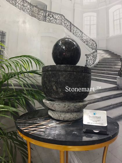 A different angle of the granite modern tabletop fountain, showing the reflection of light on the wet sphere.