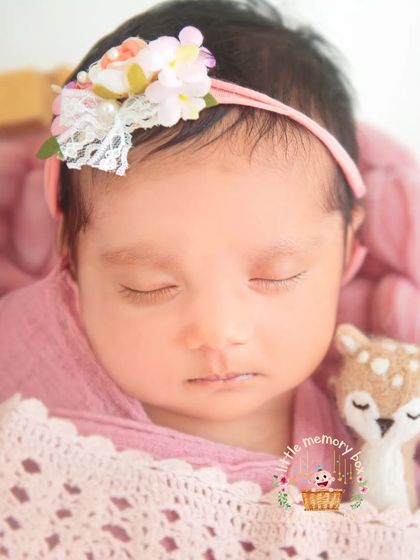 Another view of this peaceful pose, showing the soft pink layers and the delicate floral headband. It's a classic and beautiful look for a baby girl.