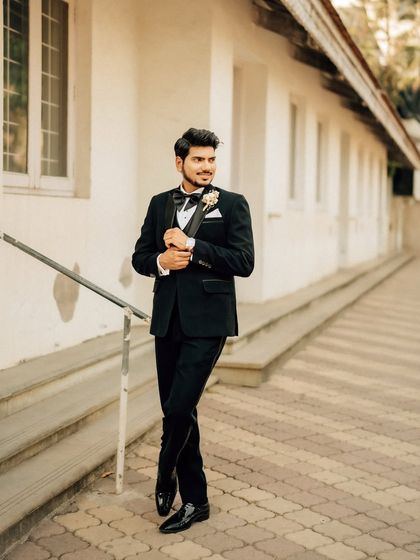 A classic, full-length portrait of the groom looking sharp in his tuxedo. The outdoor setting provides a clean and timeless background.