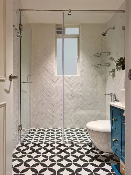 This bathroom renovation shows how I love to play with pattern and color. By contrasting bold, geometric floor tiles with a clean, white herringbone pattern on the walls, I created a high-impact look. The custom teal vanity adds a pop of personality, turning a functional room into a joyful space.