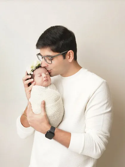 A father gives his sleeping newborn a gentle kiss on the forehead. It's these small, tender gestures that tell the biggest stories of love.