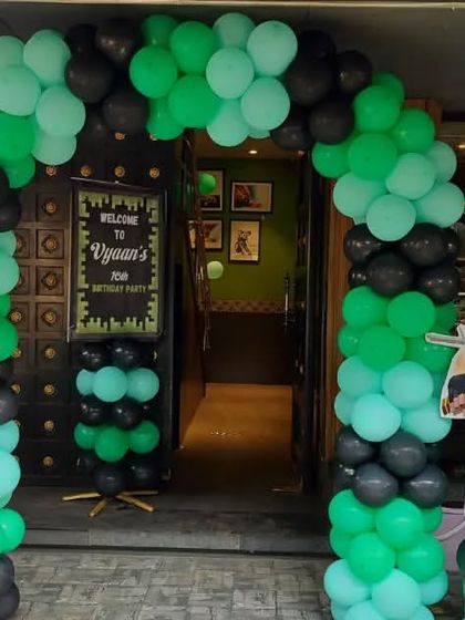The entrance to the Minecraft party, featuring a green and black balloon arch and character cutouts to welcome fellow gamers.
