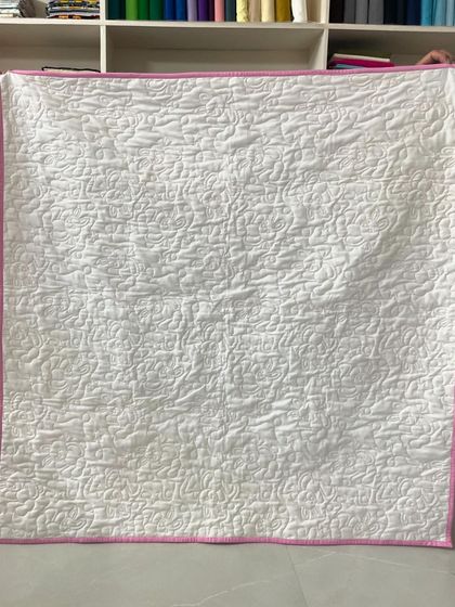 The solid white back of the quilt, which highlights the dense, loopy quilting pattern.
