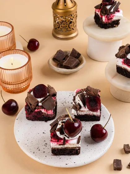 Mini Black Forest-inspired cakes, styled with fresh cherries and chocolate shavings. The composition is playful yet elegant, perfect for a modern patisserie.