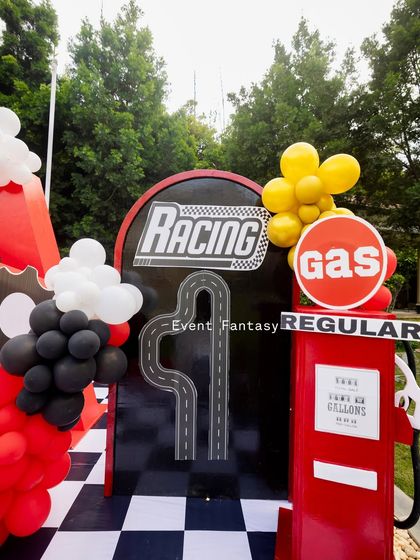 A vintage-style red gas pump and a "Racing" sign, adding authentic details to the pit stop area of the party.
