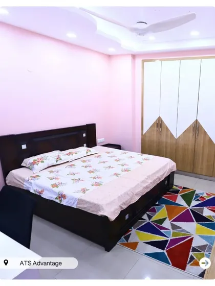 A simple yet cheerful bedroom with pink walls and modern two-toned wardrobes. The colorful geometric rug adds a playful touch.