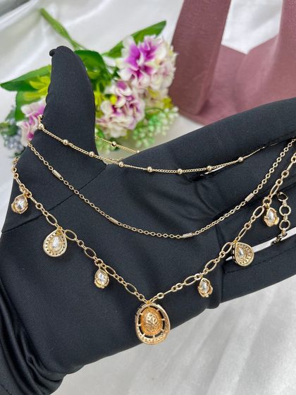 The Saanvi Royal Three-Layer Set. This delicate gold-plated set features three distinct chains with small pendants, offering a trendy, layered look in a single piece.