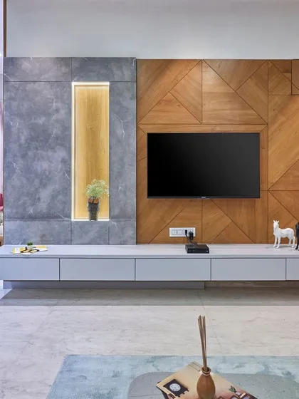 This custom-designed TV unit features a mix of geometric wood paneling and a cool grey stone-finish accent. The floating console keeps the look clean and modern, providing ample storage without the bulk.