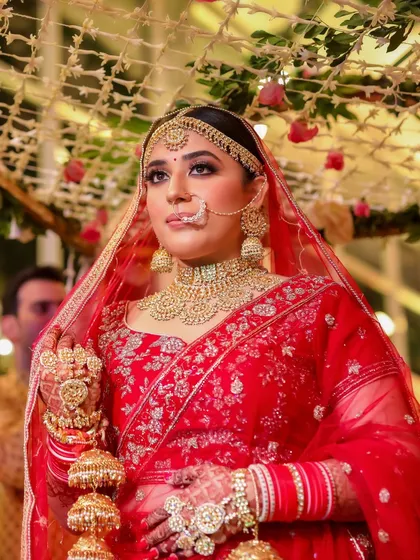 This candid shot under the mandap captures the bride's serene beauty. The soft lighting highlights the glowing finish of her makeup and the richness of her red lehenga.