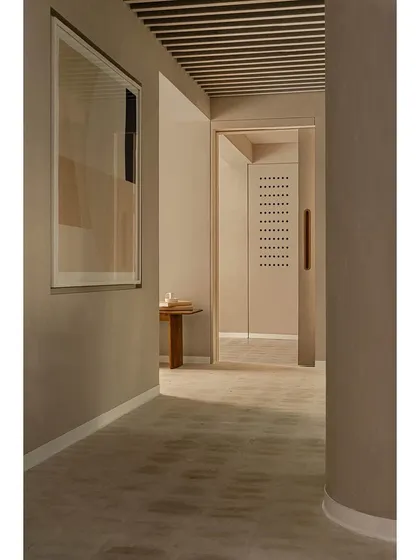 The corridor of the 'Crème' wellness center showcases our concept of 'restrained luxury'. We used a seamless, creamy wall finish, curved forms, and carefully placed lighting to create a fluid, calming journey for clients, transforming a simple passage into a sensory experience.