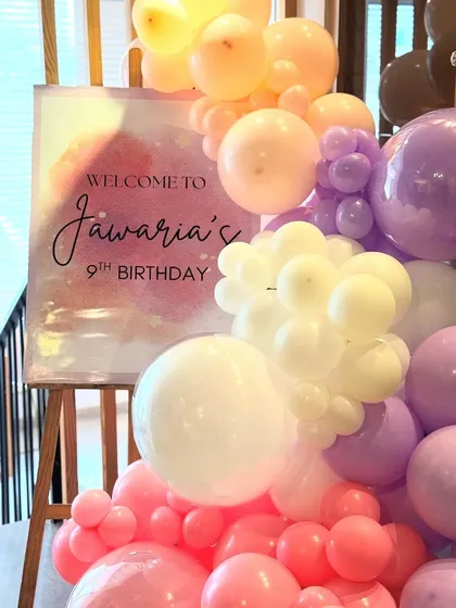 Another angle of the personalized welcome sign for Jawaria's birthday, showing how the balloon garland elegantly frames the sign. The soft, multi-colored balloons create a warm and inviting welcome for guests.