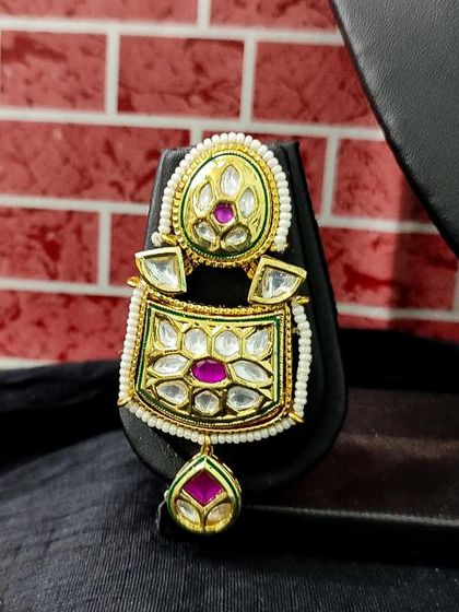 The matching earring for this set, featuring the same green and pink color combination.