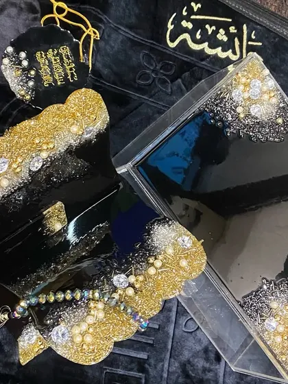 This luxurious black, gold, and silver combo set is a popular choice for a bridal gift. It includes a premium velvet prayer mat, a personalized acrylic Quran box, a resin Quran stand (rehal), a crystal tasbeeh, and a matching car hanging.