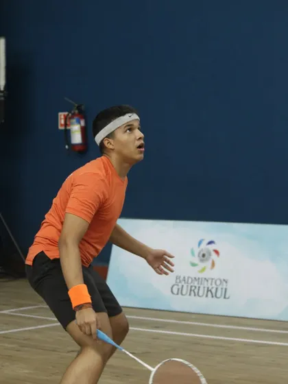 A young player watches the shuttlecock intently, preparing for a high shot during the Gautam Thakkar Memorial Championship.