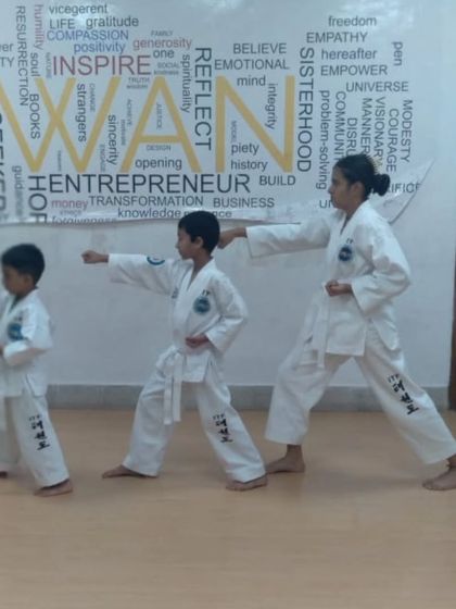 A female black belt instructor leads two young students in practicing their punching form. It's inspiring for kids to learn from accomplished women martial artists.
