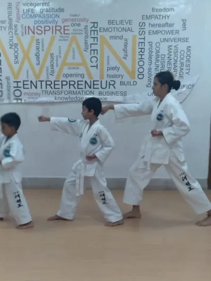 A female instructor teaching the basic punching stance to two young boys, showing progression and mentorship.