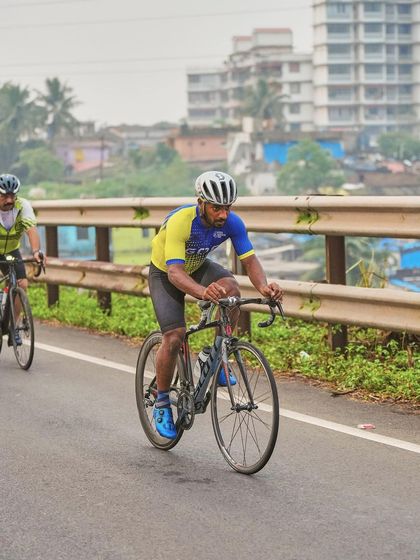 Two cyclists from the Goan team ride in sync during a practice session. This image captures the teamwork and pacing essential for road cycling events, set against an urban backdrop.