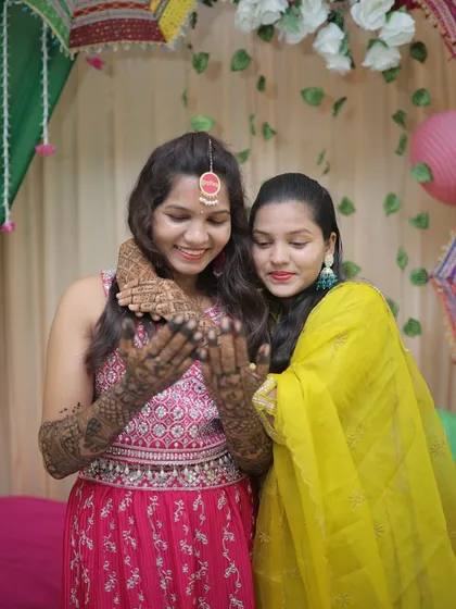 A sweet moment between a bride and her sister, both admiring the fresh mehendi. These are the precious memories that surround a wedding.